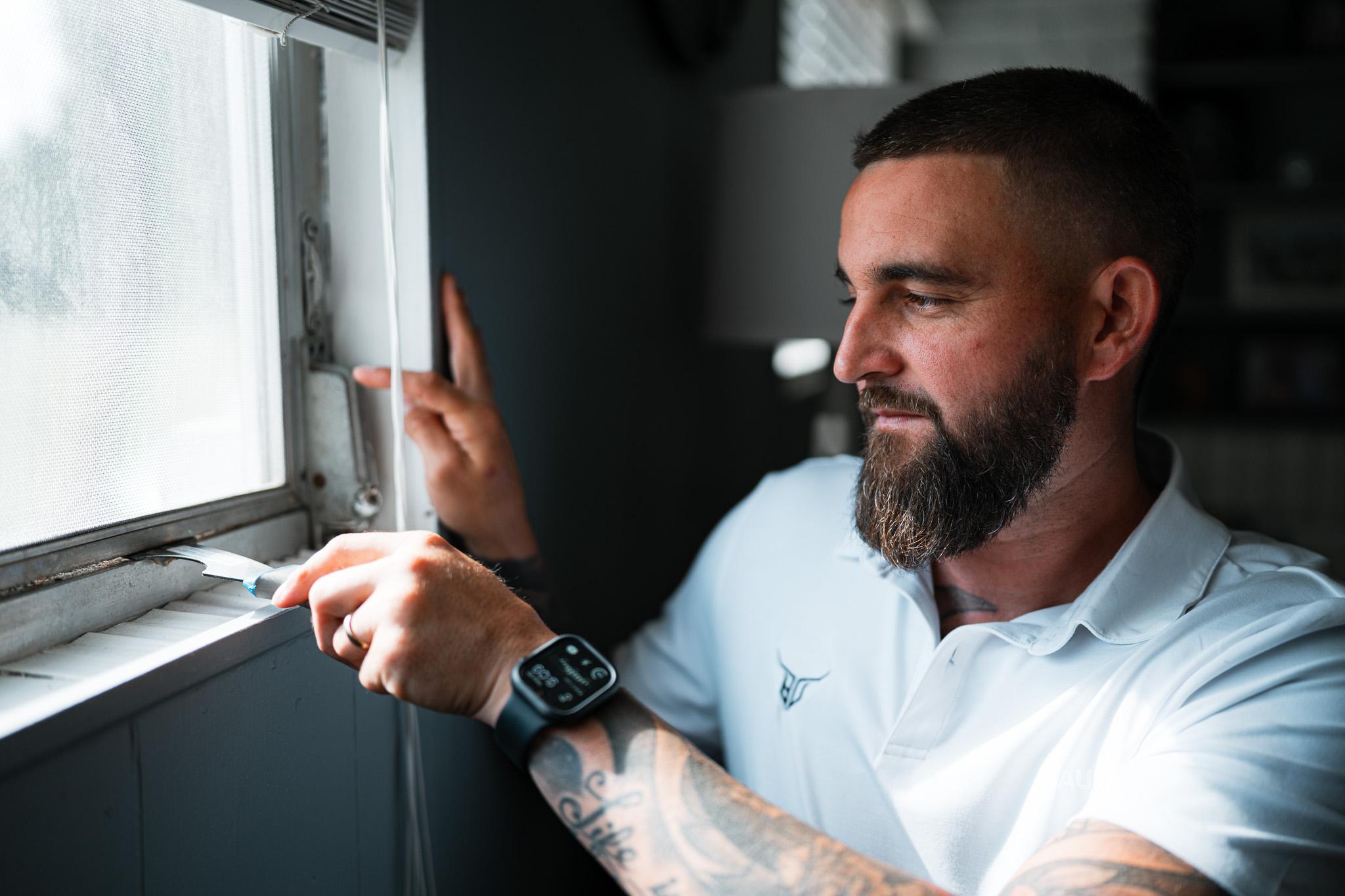 Logan Deel working on a window frame with a putty knife