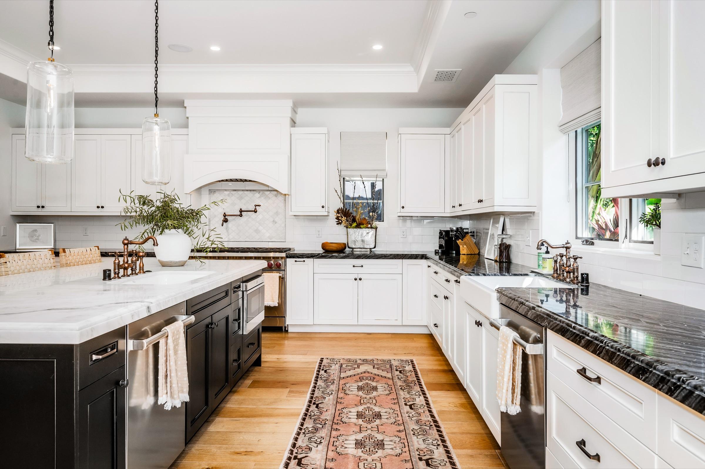 Remodeled kitchen with white cabinets, dark stone counters, an island and hardwood floors
